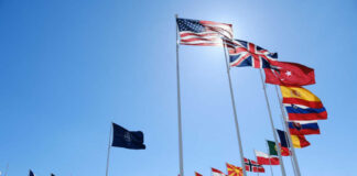 Many national flags flying in clear blue sky
