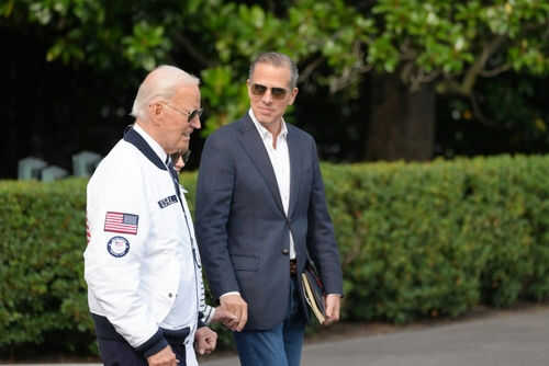 joe-biden-hunter-biden_2494537949 Two men walking outside near green bushes
