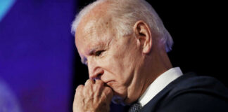 elderly man in suit resting chin on hand in thought