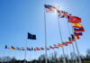 NATO Scrambles: Ukrainian Drones Breach Airspace! Flags of multiple countries against blue sky