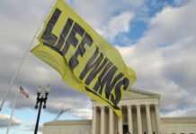 Yellow Life Wins flag near government building cloudy sky