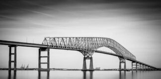 A large bridge spanning over a calm body of water in black and white