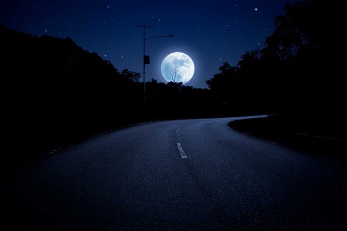 Dark,Night,Illuminated,By,The,Full,Moon.,Moonlight,Over,The Emergency responders at an overturned, smoking car on a roadway