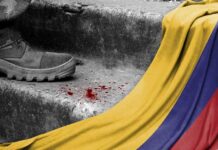 A military boot on concrete steps with blood stains and a Colombian flag draped nearby