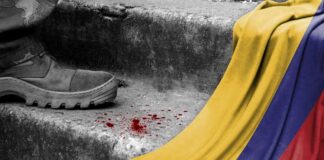 A military boot on concrete steps with blood stains and a Colombian flag draped nearby