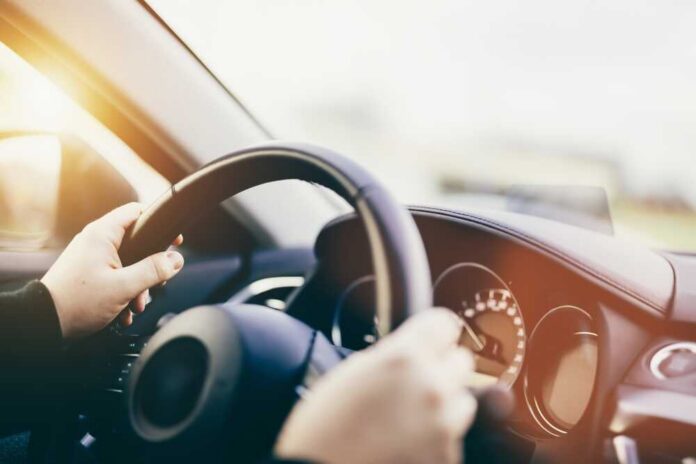 Hands gripping a steering wheel inside a car