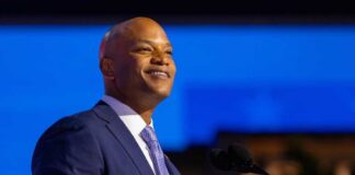 A confident speaker in a suit smiling while addressing an audience