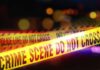 Killer’s Bizarre Claim: ‘I’m The Third Victim!’ Yellow police tape marking a crime scene with blurred lights in the background