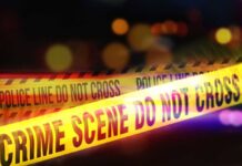 Killer’s Bizarre Claim: ‘I’m The Third Victim!’ Yellow police tape marking a crime scene with blurred lights in the background