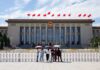 Tourists in front of the Great Hall of the People with Chinese flags
