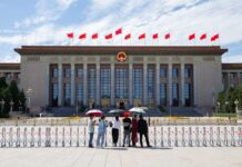 Tourists in front of the Great Hall of the People with Chinese flags