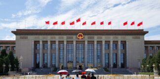Tourists in front of the Great Hall of the People with Chinese flags