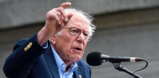 A man passionately speaking at a microphone during a public rally