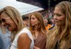Three women at a race event, with one laughing and another looking thoughtful