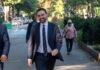 A man in a suit walking happily in a city park