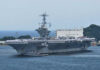 Iranian Vessels Disabled: US Navy Strikes Back Aircraft carrier with sailors on deck at harbor.