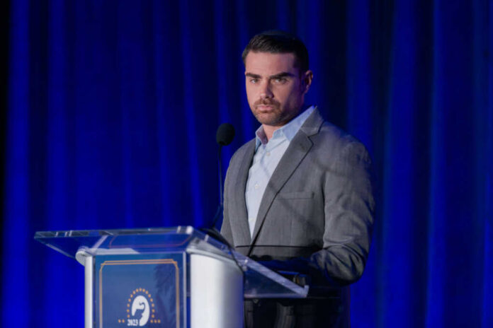 ben-shapiro-speaking2381827657jpg-1 A man speaking at a podium in a suit