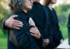People comforting each other at a funeral outdoors