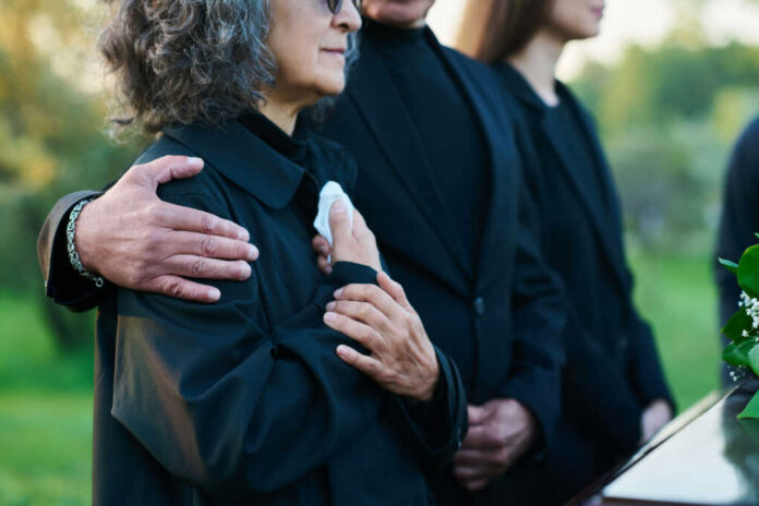 People comforting each other at a funeral outdoors