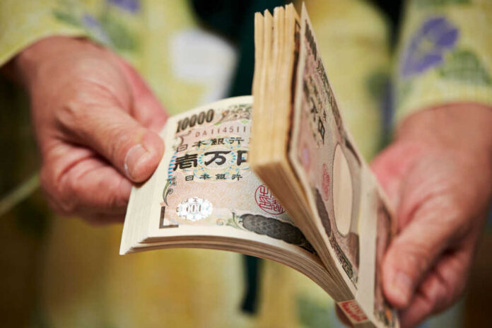 hand-holding-japanese-money2173824659jpg Hands counting a thick stack of Japanese yen banknotes