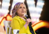 Party Civil War: Hillary Turns On Biden Person in yellow jacket speaks into microphone.