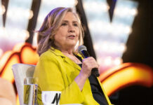 Party Civil War: Hillary Turns On Biden Person in yellow jacket speaks into microphone.