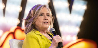Person in yellow jacket speaks into microphone.