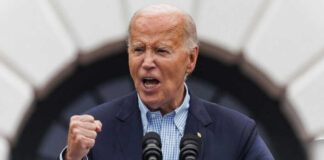 older man speaking passionately at a podium with two microphones