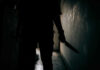 Silhouette of person holding knife in dark corridor