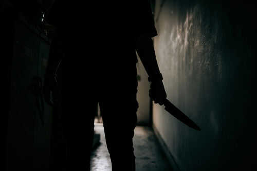 murderer2168912605 Silhouette of person holding knife in dark corridor
