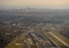 Aerial view of an airport terminal with a control tower and surrounding greenery