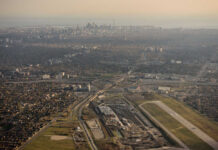 £22B Mega-City Rises From Shuttered Airport Aerial view of an airport terminal with a control tower and surrounding greenery