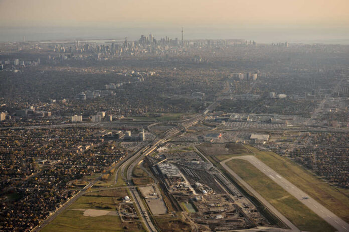 Downsview,Airport,And,Yorkdale,Shopping,Centre,In,North,York,With Aerial view of an airport terminal with a control tower and surrounding greenery