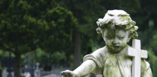 Weathered angel statue holding a cross in a cemetery