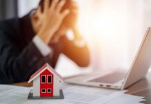 Veterans’ Lifeline Hides Second Mortgage A businessman with his head in his hands, stressed over paperwork and a model house on the table