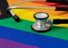 Medicaid Shock: States Fund Teen Trans Care A stethoscope resting on a rainbow flag background