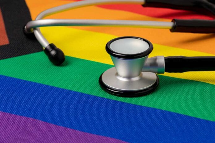 Rainbow,Pride,Flag,And,Stethoscope.,Transgender,And,Lgbtq+,Healthcare,And A stethoscope resting on a rainbow flag background