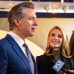 Cronyism Charge Erupts Over Flood Board A man speaking at a public event with two women smiling nearby