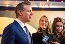 Cronyism Charge Erupts Over Flood Board A man speaking at a public event with two women smiling nearby