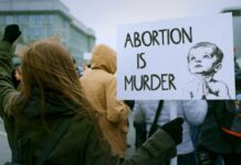 Supreme Curveball: Abortion Pill Fight Isn’t Over Person holding a sign that reads 'Abortion is Murder' at a protest