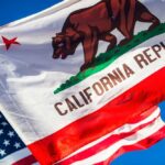 Outsiders Shake California – Pratt Nears Runoff, Hilton Surges California Republic flag waving alongside the American flag against a blue sky