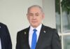 Netanyahu Defies Trump, Risk Soars A view of destroyed buildings with smoke rising in the background