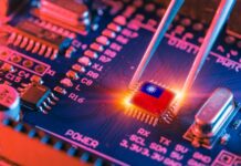 Tweezers placing a microchip on a blue circuit board