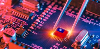 Tweezers placing a microchip on a blue circuit board