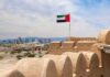 Arsonist–Firefighter: Abu Dhabi’s Iran Play UAE flag waving atop a historic fort with a city skyline in the background