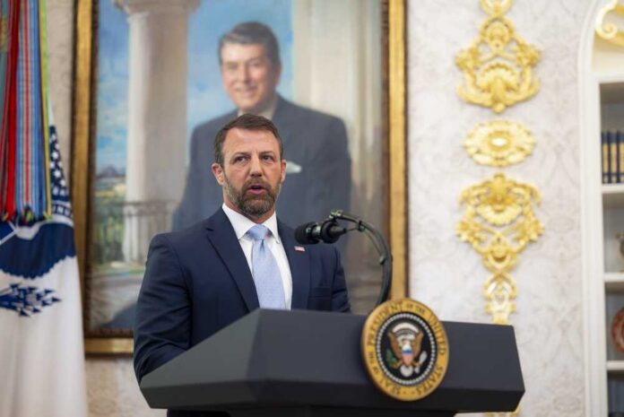 Man in suit speaking at a podium in an ornate room
