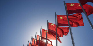 Multiple Chinese flags waving against a clear blue sky