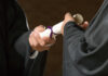 Two individuals exchanging a diploma during a graduation ceremony