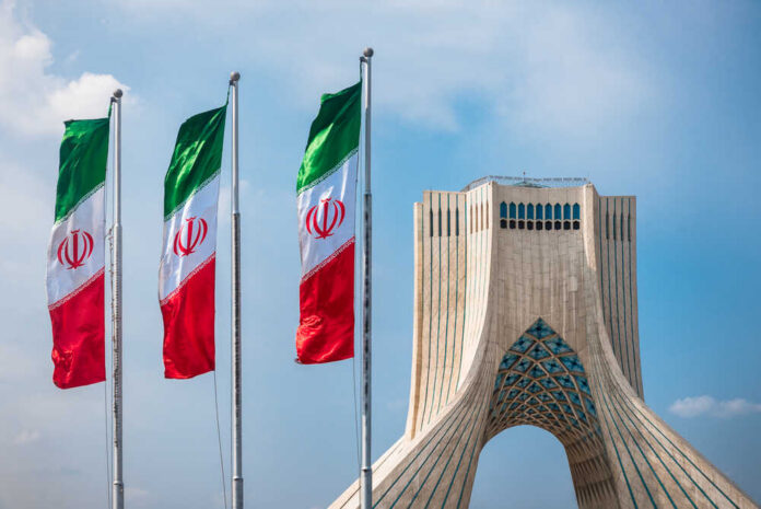 Tehran,,Iran,-,Oct,25,,2016,:,Azadi,Tower,With Three Iranian flags in front of the Azadi Tower against a blue sky