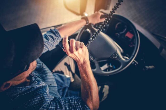 A truck driver using a microphone while driving